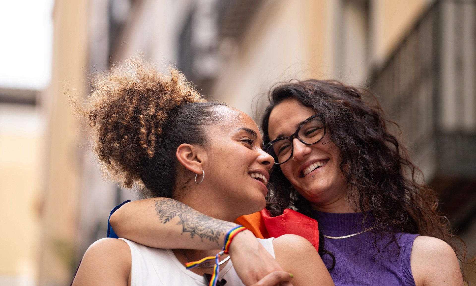 Headshot of two multiethnic lesbian women in love hugging and smiling enjoying time together