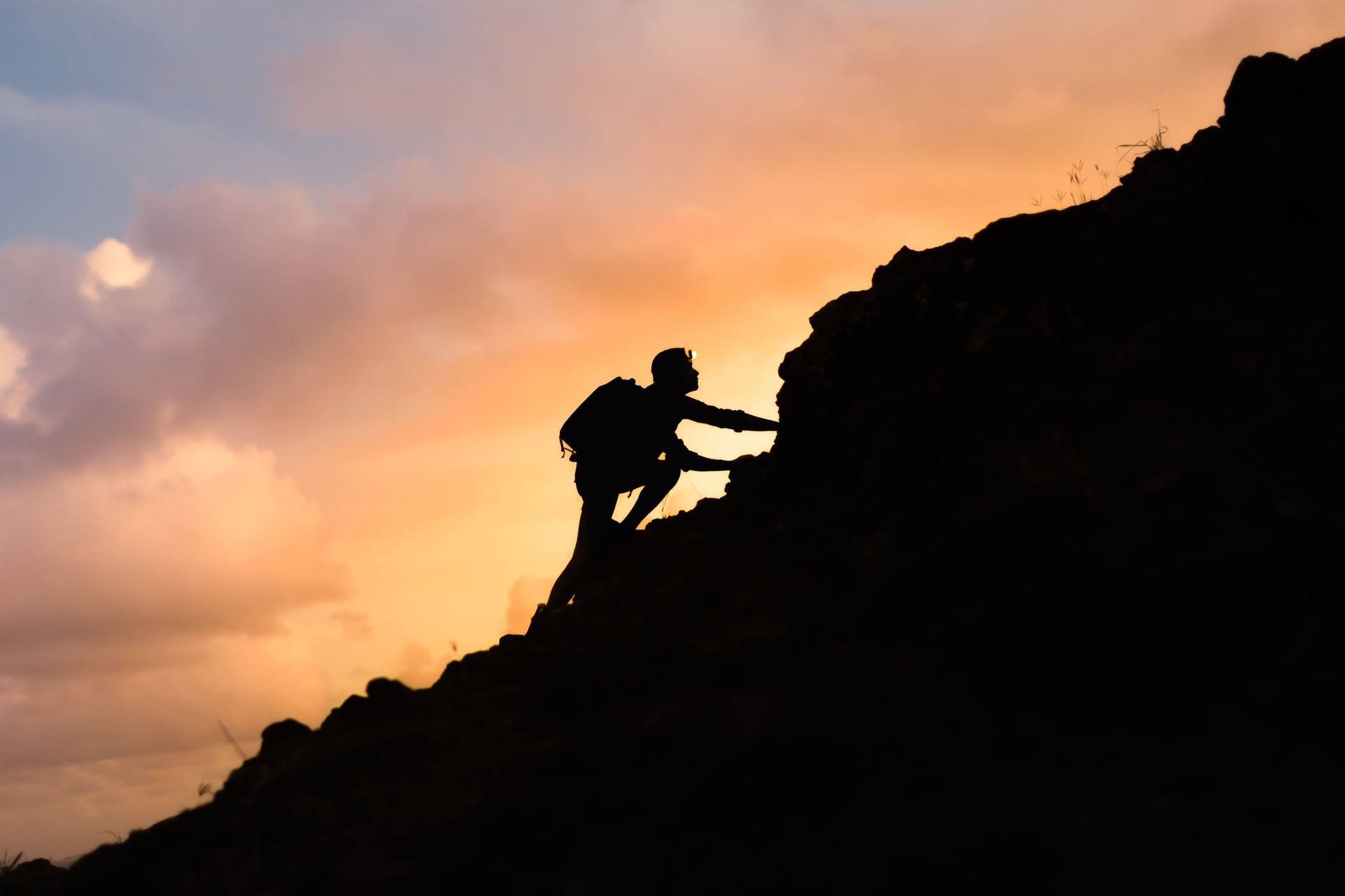 Male hiker climbing steep mountain.