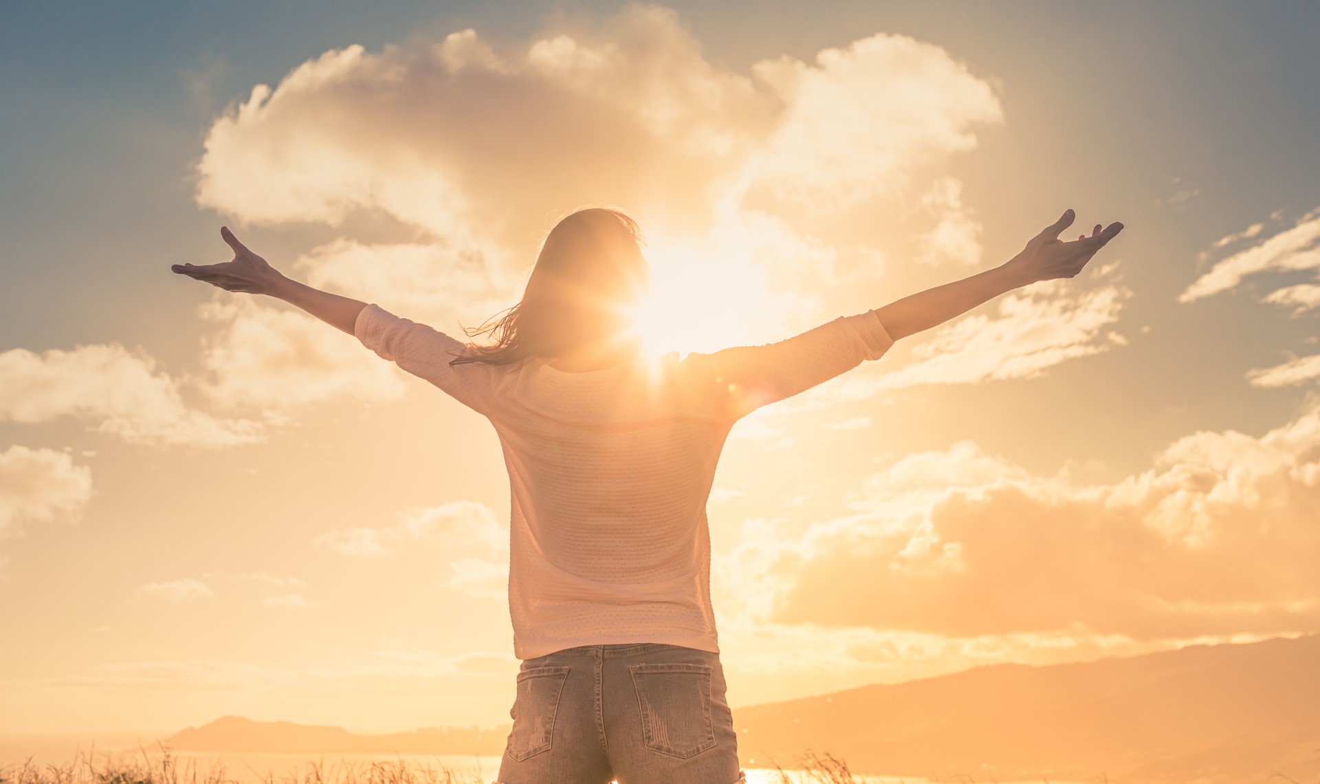 Young woman with hands up the morning sun light finding happiness, peace and hope in nature